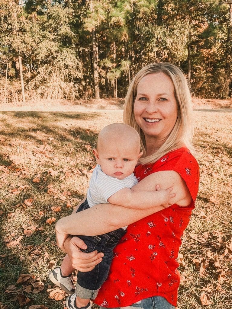 Woman holding baby in front of the woods