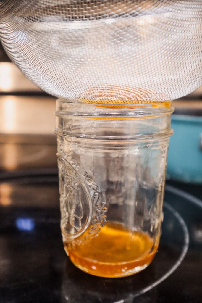 straining apple crisp macchiato syrup into mason jar