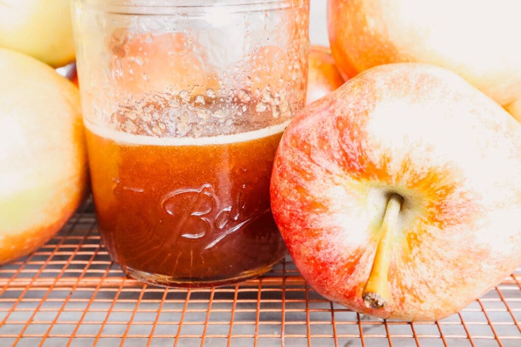 Apple crisp macchiato syrup in mason jar surrounded by apples