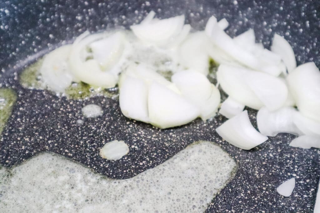 Sliced onions frying in skillet